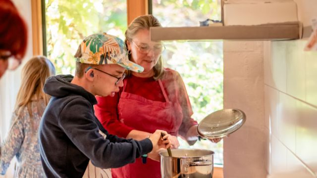 Betreuerin und ein Junge beim Kochen